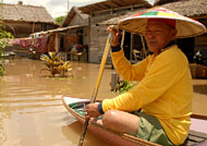 Pak Muham menaiki perahu di sekitar rumahnya yang terendam banjir