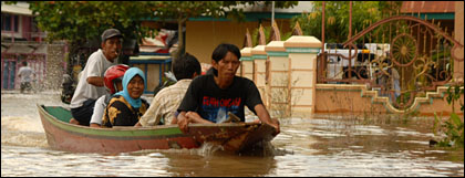 Warga menggunakan perahu ketiting di atas jalan yang terendam banjir