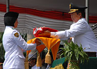 Pj Bupati Kukar H Sjachruddin menyerahkan bendera Merah Putih kepada siswi SMAN 1 Samboja, Intan Safitri
