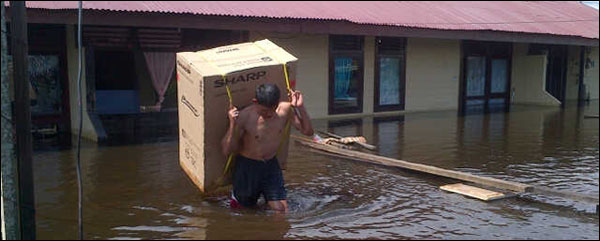 Seorang anggota Polsek Muara Kaman menyelamatkan barang dari asrama polisi yang telah terendam banjir, Jum'at (03/05) pagi