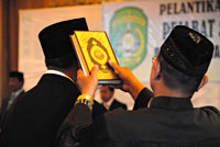 Seorang rohaniawan mengangkat kitab suci Al Qur'an pada saat pengambilan sumpah jabatan terhadap ratusan pejabat dari 18 kecamatan se-Kukar