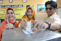 Bupati Rita Widyasari bersama ibu dan suaminya memberikan suara di TPS 3 Panji 