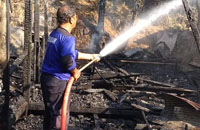 Petugas BPBD Kukar melakukan pendinginan dengan menyemprotkan air ke arah puing-puing kebakaran