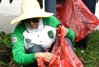 Bupati Rita Widyasari memasukkan sampah yang ditemukannya ke dalam kantong plastik 
