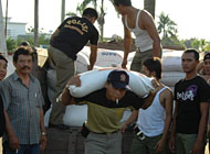 Seorang anggota Satpol PP mengangkut karung beras yang akan dikapalkan menuju wilayah pedalaman yang terendam banjir