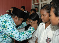 Wabup Samsuri Aspar secara simbolis memasangkan sebuah kacamata minus bantuan IKBJ kepada pelajar SD dari keluarga kurang mampu