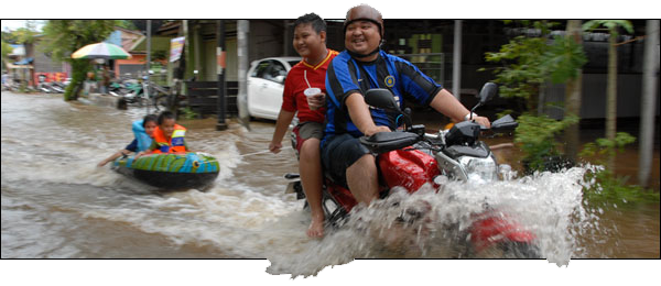 Warga Tenggarong memanfaatkan jalanan yang tergenang banjir untuk bermain air