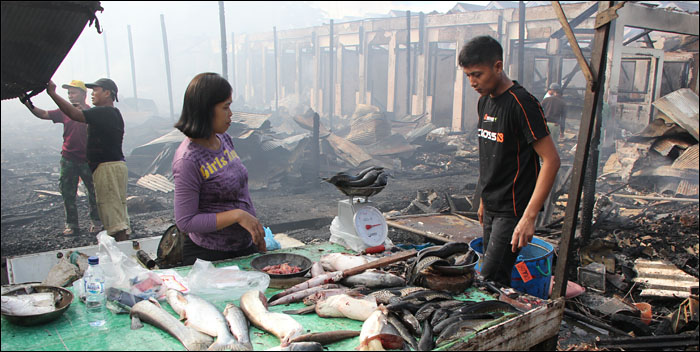 Salah satu pedagang ikan di Pasar Tangga Arung tetap berjualan meski petak dan stok ikan yang mereka simpan ikut ludes terbakar   