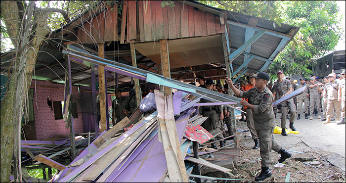 Petugas Satpol PP Kukar menumpuk papan yang baru dibongkar dari bangunan ilegal eks warung kopi di Tenggarong Seberang