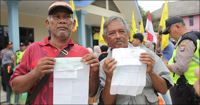 Dua warga kampung Batu Dinding menunjukkan bukti setoran pembayaran pasang baru listrik yang telah dibayarkan sejak 2014 silam