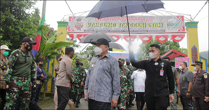 Di bawah guyuran hujan gerimis, Gubernur Kaltim H Isran Noor meninjau pelaksanaan PPKM di Kampung Tangguh Desa Sumber Sari, Loa Kulu  