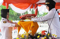 Bupati Kukar Rita Widyasari menyerahkan bendera Merah Putih kepada Siti Mariam untuk dikibarkan