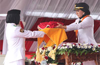 Bupati Rita Widyasari menyerahkan bendera Merah Putih kepada siswi SMK Muhamadiyah Loa Janan, Riris Nuria Ananda, untuk dikibarkan