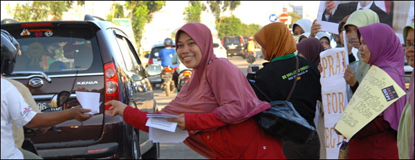 Salah seorang peserta aksi damai APM Kukar untuk Mesir membagi-bagikan selebaran kepada warga Tenggarong yang melintas