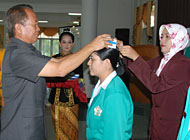 Pj Bupati Kukar H Sjachruddin memasang kap di kepala salah seorang mahasiswa Akbid Kutai Husada Tenggarong