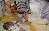 Dengan penuh kasih sayang, Bupati Rita Widyari memberikan minum susu botol kepada bayi Rendy