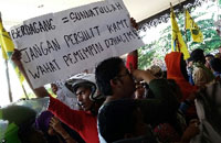 Para pedagang membentangkan lembaran kertas berisi protes 