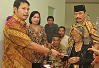 Kepala Dinsos Kukar Mursito menyerahkan bantuan secara simbolis kepada salah seorang lansia di Tenggarong