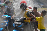 Di jalanan, warga menyiramkan air kepada pengendara yang melintas