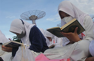 Pelajar putri dari salah satu sekolah tampak khusuk membaca Al Quran