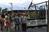 Petugas dan warga setempat mengamati puing-puing bangunan yang terbakar di Bukit Jering, Muara Kaman