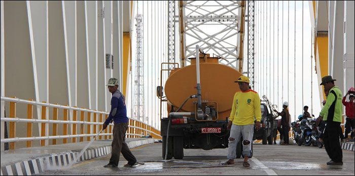 Seorang petugas membersihkan jalur di sepanjang jembatan Kartanegara jelang soft opening, Senin (07/12) sore kemarin
