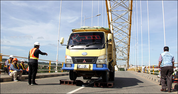 Satu buah truk berkapasitas 15 ton melewati balok setinggi 20 cm untuk menghasilkan getaran pada uji beban dinamis Jembatan Kartanegara  