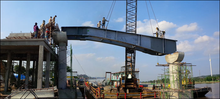 Dengan menggunakan crane, rangka baja lantai jembatan Kumala diangkat dan dipasang di atas pilar beton