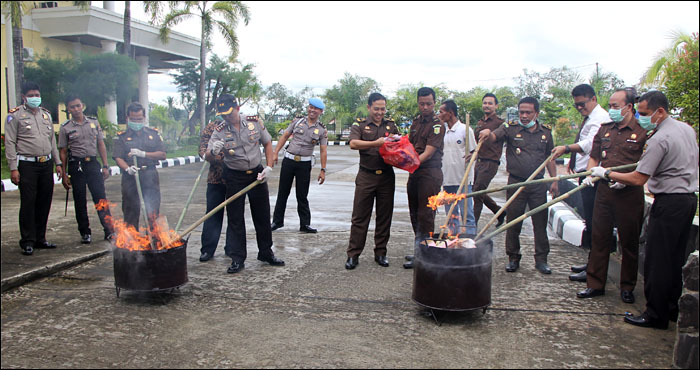 Para pejabat penegak hukum melakukan pemusnahan barang bukti dengan cara dibakar