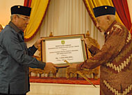 Bupati Kutim Isran Noor menyerahkan dana hibah secara simbolis kepada Sultan Kutai HAM Salehoeddin II