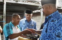 Disaksikan Pj Bupati H Chairil Anwar, Sekkab Kukar Edi Damansyah menyerahkan bantuan kepada Kades Kota Bangun Seberang