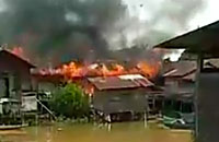 Kobaran api yang melalap rumah warga terlihat dari seberang sungai Jembayan