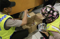 Dua anggota Polsek Muara Jawa memeriksa film-film yang diperdagangkan di salah satu toko DVD/VCD