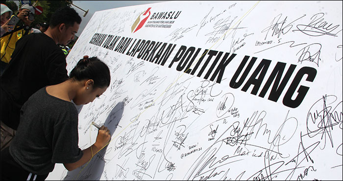 Warga membubuhkan tanda tangan di atas baliho sebagai dukungan terhadap gerakan tolak dan laporkan politik uang yang dikampanyekan Bawaslu Kukar