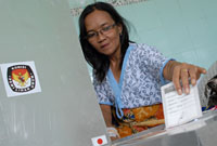 Seorang pasien RSUD AM Parikesit memasukkan surat suara yang telah dicoblos ke dalam kotak suara