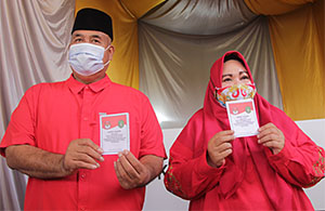 Bupati Kukar Edi Damansyah dan istri menunjukkan surat suara Pilkada Kukar 2020 di TPS 22 Timbau