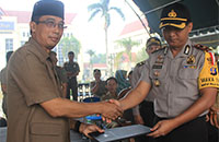 Plt Sekkab Kukar H Marli menyerahkan berita acara penyerahan BKO Satlinmas kepada Wakapolres Kukar Kompol Indratmoko