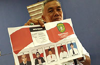Petugas di TPS 3 Desa Rempanga menunjukkan surat suara yang akan dicoblos warga yang mempunyai hak pilih