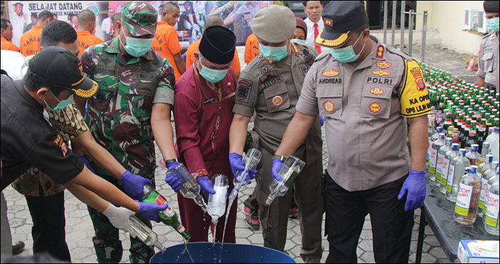 Pemusnahan barang bukti minuman keras dilakukan dengan menuang isi botol ke dalam bak sebelum dibuang ke selokan