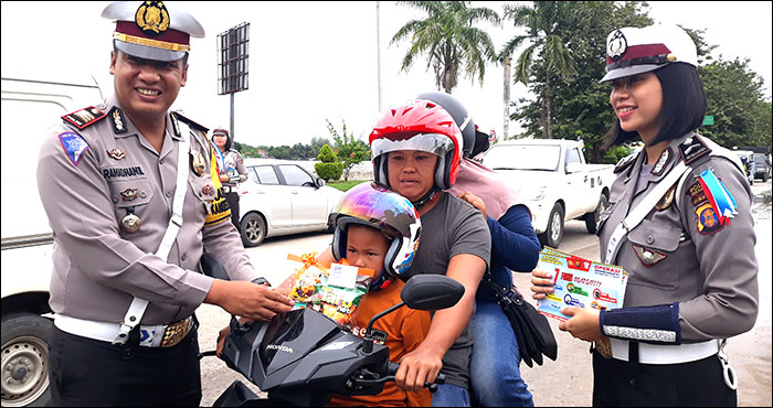 Kasat Lantas Polres Kukar AKP Ramadhanil menghadiahi souvenir makanan ringan kepada seorang anak yang telah mengenakan helm saat dibonceng orangtuanya