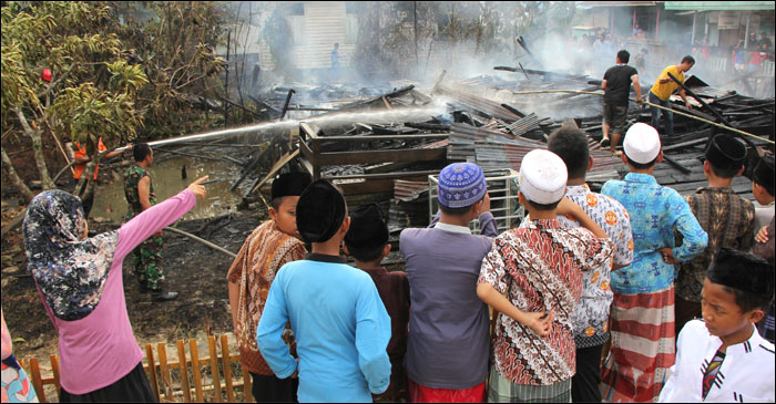 Santri Ponpes Ribathul Khail memperhatikan para petugas PMK yang masih melakukan pendinginan di puing-puing rumah guru pesantren yang ludes terbakar