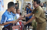 Plt Kepala Dispora Kukar Tajuddin menyerahkan bingkisan kepada anak-anak peserta khitanan massal