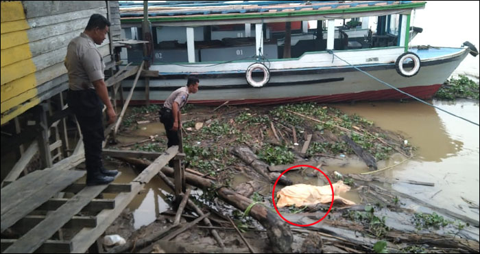 Petugas Polsek Tenggarong Seberang mengamati jasad Fredi yang telah ditutup dengan kain di sekitar dermaga desa Separi