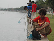 Seorang remaja memasukkan ikan hasil tangkapannya