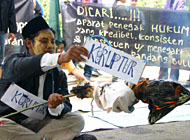 Seorang demonstran yang berperan sebagai koruptor ketika membakar sebuah boneka koruptor