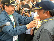 H Syaukani HR mengalungkan pin kepada Samsuri Aspar yang menjadi Ketua Tim Sukses