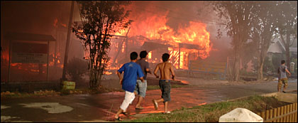 Sejumlah warga berlari di sepanjang Jalan Muso Bin Salim ketika api masih berkobar hebat melahap rumah warga RT V Kelurahan Melayu, Tenggarong, Selasa (11/04) sore