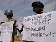 Pengunjukrasa membentangkan poster berisi seruan terhadap pemerintah untuk menghentikan komersialisasi atas pendidikan