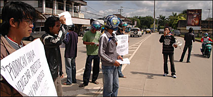 Sambil membentangkan poster dan membagikan selebaran, pengunjukrasa berorasi di tengah jalan