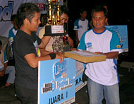 Ketua Panitia Pelaksana, Fitri (kanan), menyerahkan hadiah Juara I kepada perwakilan Destroyer Band dari Samarinda
